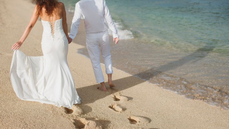 Couple walking along the seashore on their wedding day in Ibiza