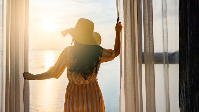 Woman opening the curtains in a hotel room in Ibiza